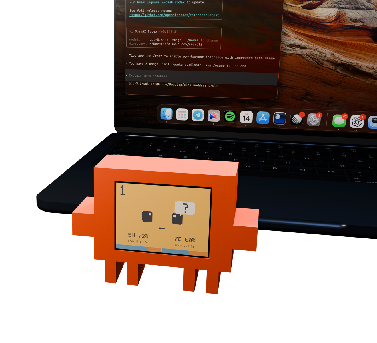 A small orange Vibe Buddy showing its attention face beside a cropped MacBook terminal